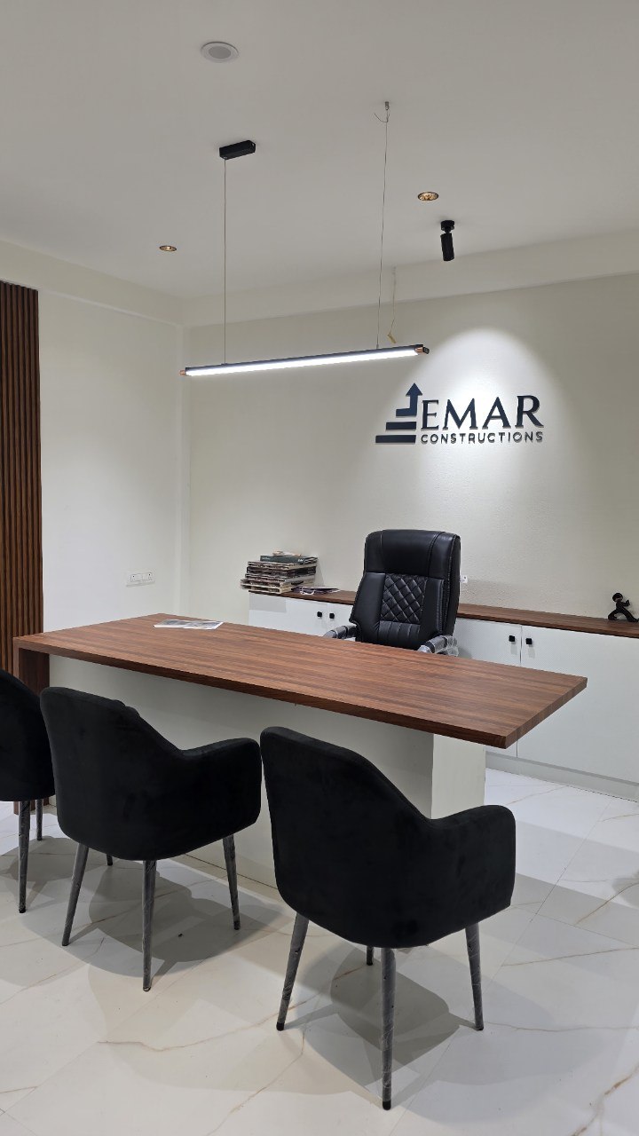 Executive cabin with long walnut desk and illuminated Emar logo wall