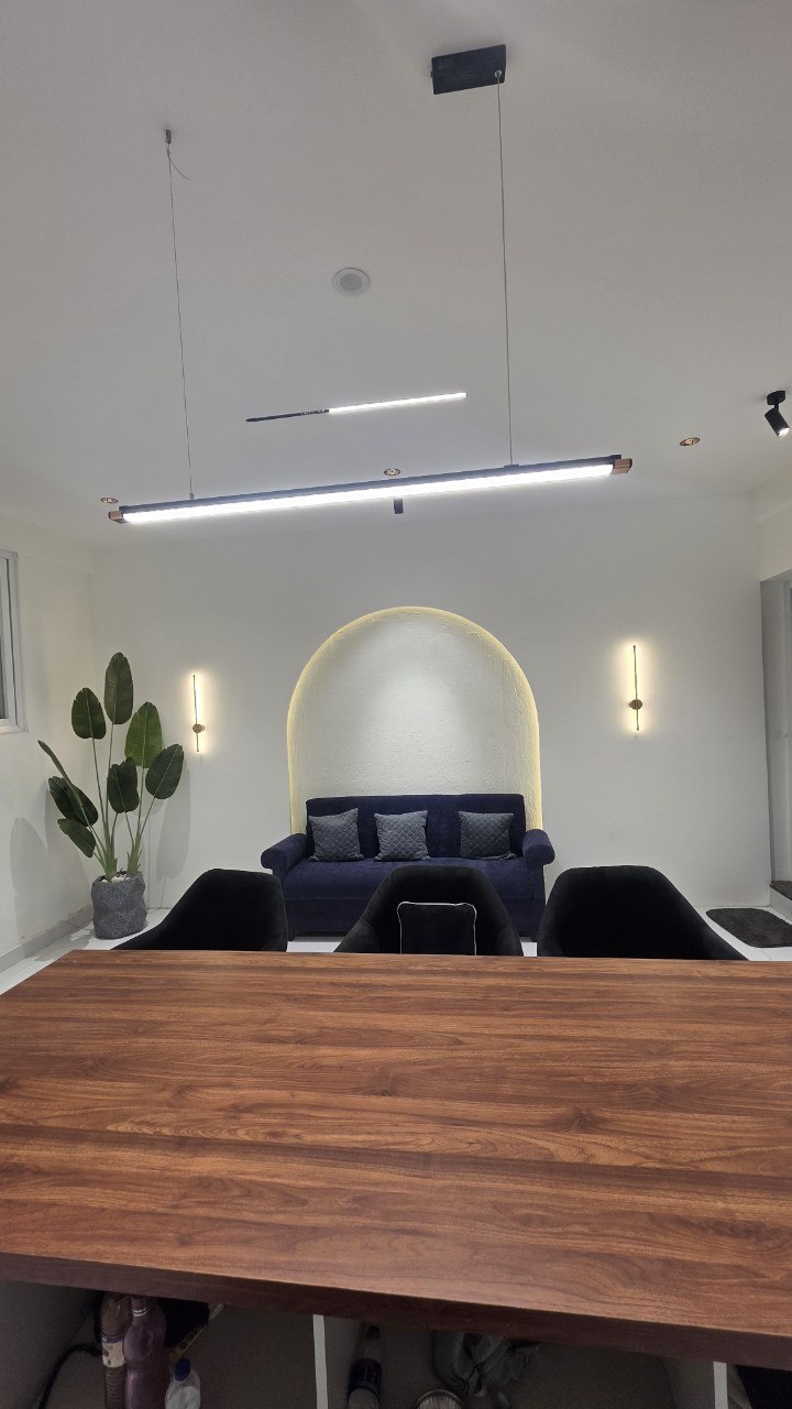 Discussion lounge with backlit arch niche, navy sofa and linear pendants