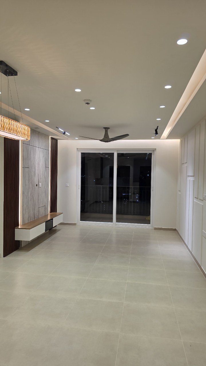 Living hall at night with fluted walnut media wall, floating console and cove lighting